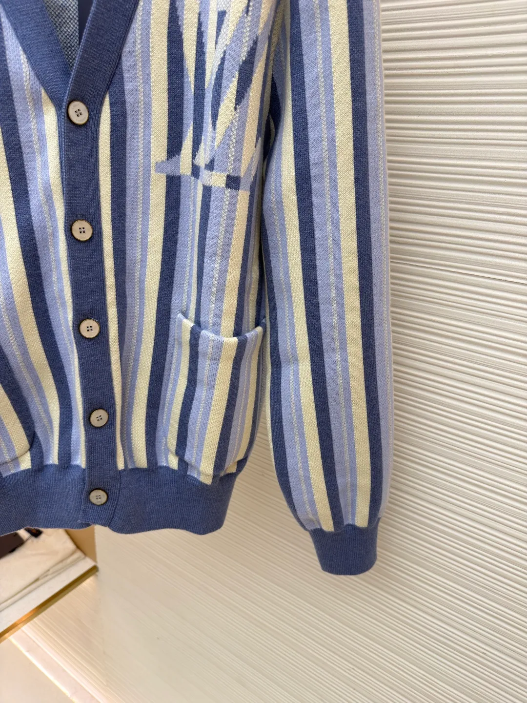 LOUIS VUITTON striped jacquard single-breasted sweater ●Original version: Purchased and developed for 15100 ●Item number: 1682314-C00 ●Fabric: wool fabric ●Technology: jacquard knitting ●Color: blue ●Version: fitted version ●Weight: about 930 grams ●Size: S-M-L-XL ●Description: This LV striped knitted cardigan is made of high-count worsted wool blended yarn. The double-ply threading process enhances the yarn's toughness. It is not easy to pill and has an outstanding drape feeling. The body of the garment adopts vertical jacquard weaving technology, with navy blue, light blue and off-white yarns interlaced with each other. The stripe width and spacing are precisely controlled by a computerized flat knitting machine, so that the color transition is natural and even. The LV letter jacquard on the left body has been debugged several times through plate making to ensure that the pattern is three-dimensional and clear. The V-neck, cuffs, and hem all use ribbing technology and are pre-shrunk to shape, making them less likely to loosen and deform after long-term wear. The buttons are made of custom-made metal, with matte sandblasting on the surface, and are hand-stitched with the seams of the body. The pockets use welting technology, and the edges are flat without jumpers. Every detail reflects the exquisite clothing craftsmanship and brand ingenuity. The overall wiring is straight and delicate, the fabric is comfortable and soft, and the color is consistent without color difference. It can be matched with the same style to create a fashionable look and control various occasions. Customized accessories, complete with three standards, same style for men and women!
